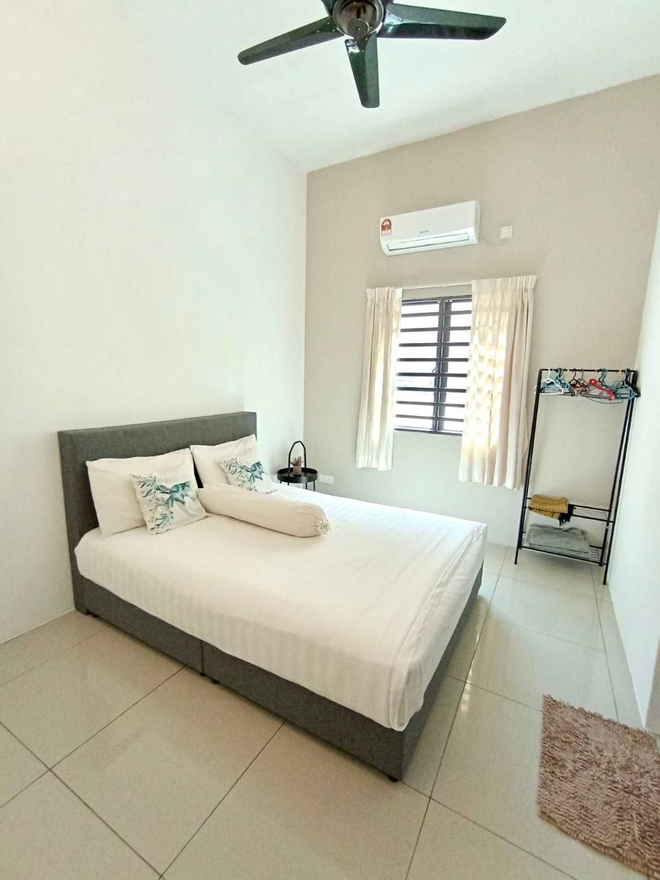 Une chambre avec un lit, un ventilateur de plafond, un appareil de climatisation, une fenêtre avec des rideaux et un porte-vêtements.