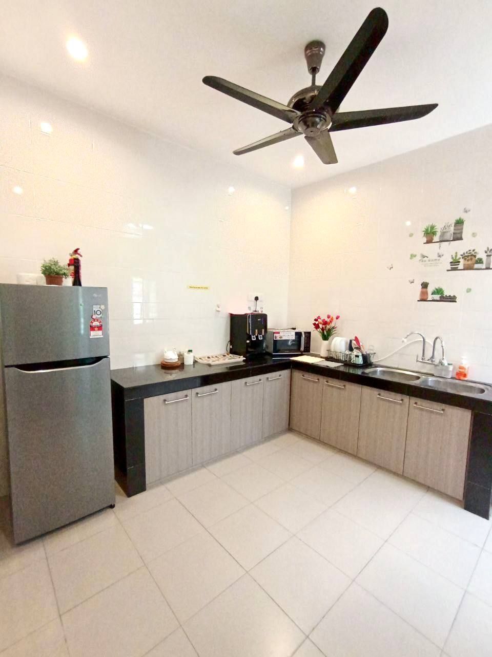 Ett modernt kök med kylskåp, mikrovågsugn, diskho och takfläkt.