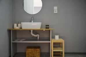 Un baño con lavamanos, espejo y estanterías blancas.
