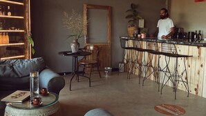 Un espace bar moderne comprenant un comptoir, des tabourets et un coin salon avec un canapé et une table ronde.