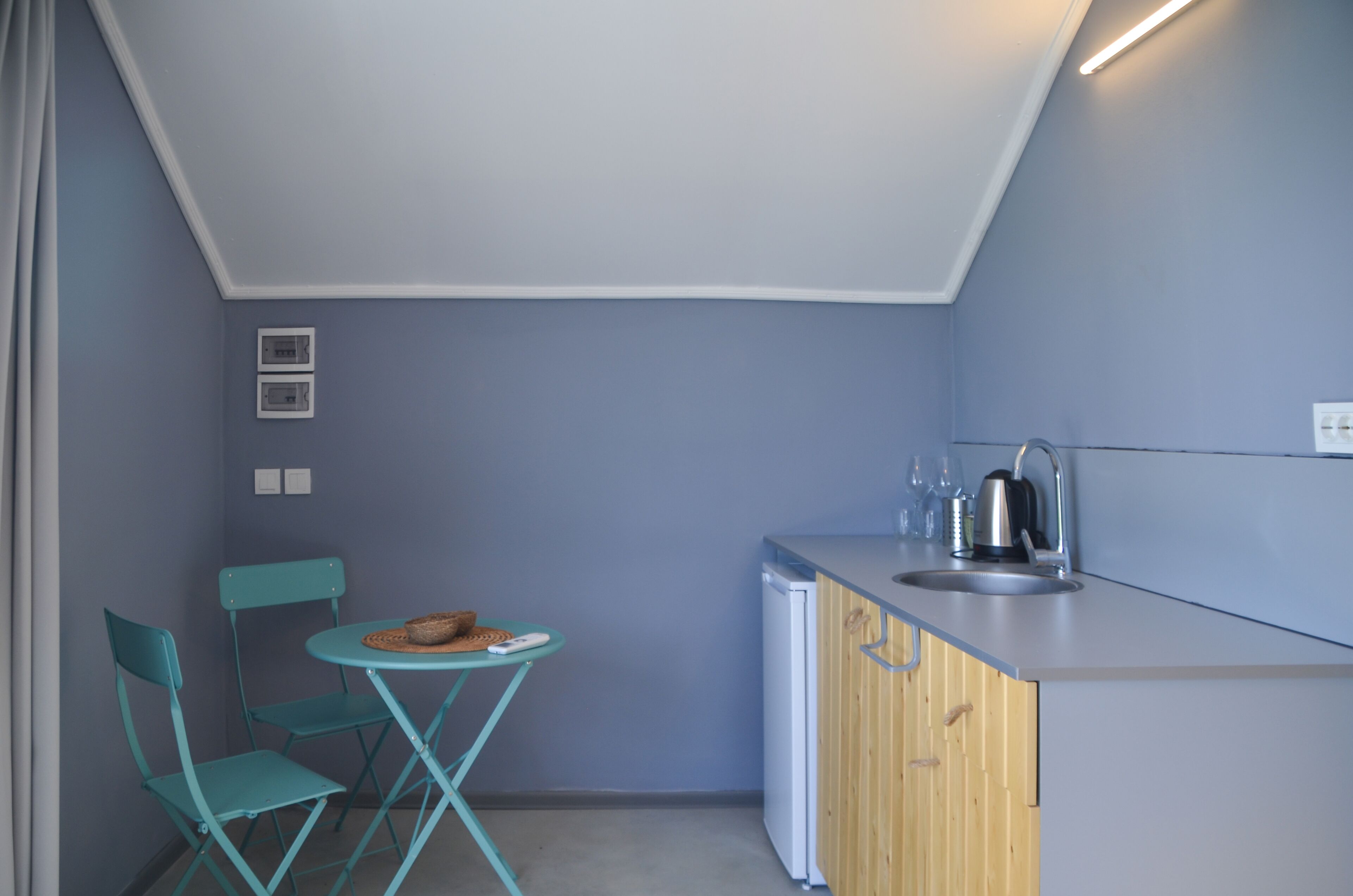 A compact kitchen with a sink, a kettle, and a small dining area with a table and chairs.