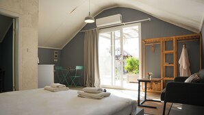 Une chambre à coucher avec un lit, un bureau, une chaise, une étagère en bois et une vue sur l’extérieur.