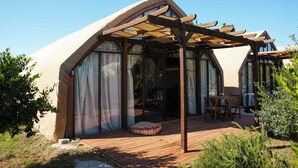 Une maison moderne dotée d’une terrasse en bois, de grandes fenêtres et d’un patio couvert.