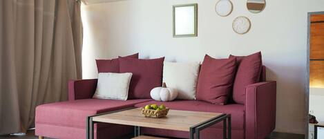 Una sala de estar con un sofá rojo, una mesa de centro de madera y una cesta de manzanas.