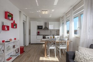 A modern kitchen with white cabinets, a microwave, and a stainless steel range hood. - Holiday Home Asteria (Labin)