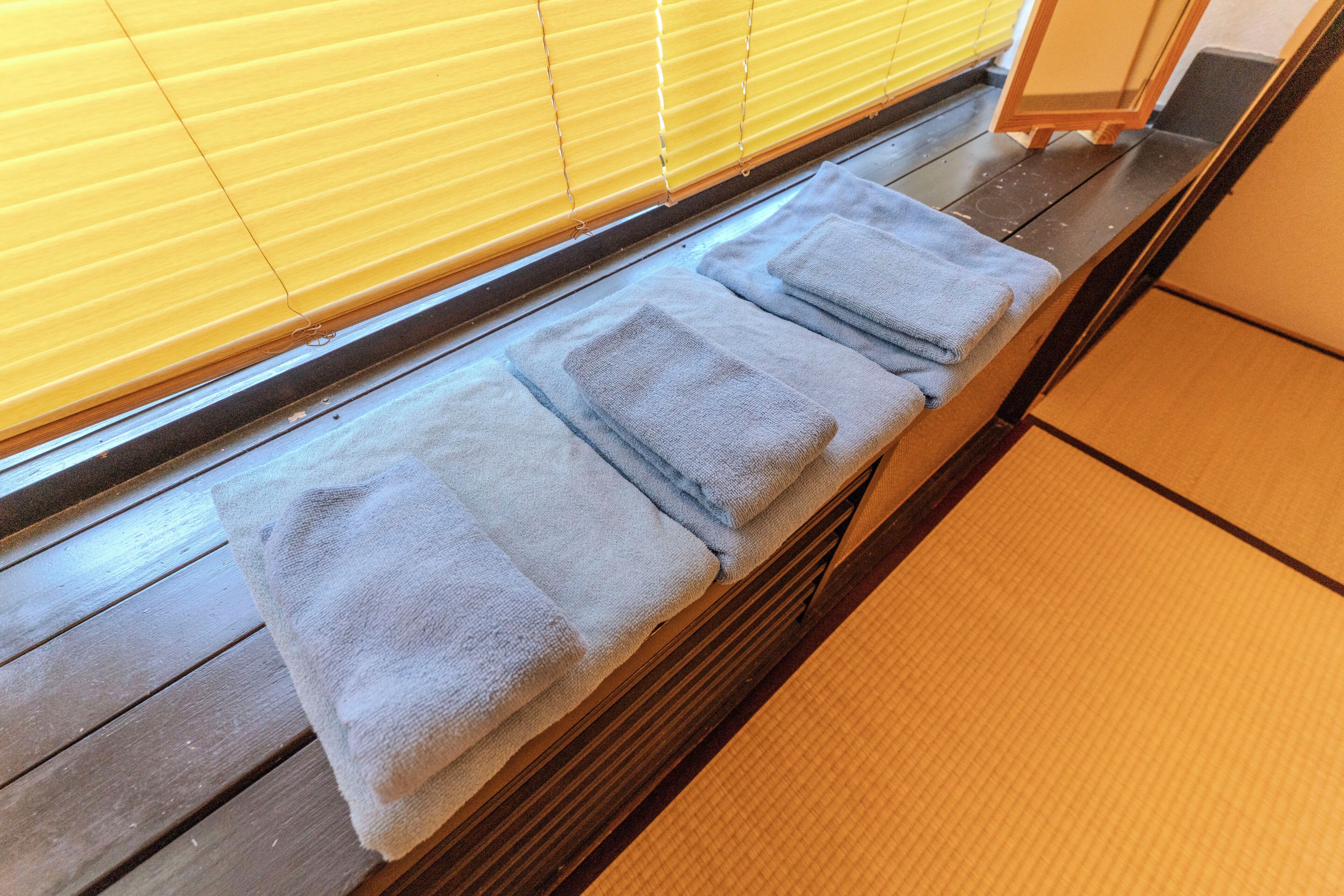 Ein Holzboden mit einer Bank und einem Fenster mit gelben Rollos.