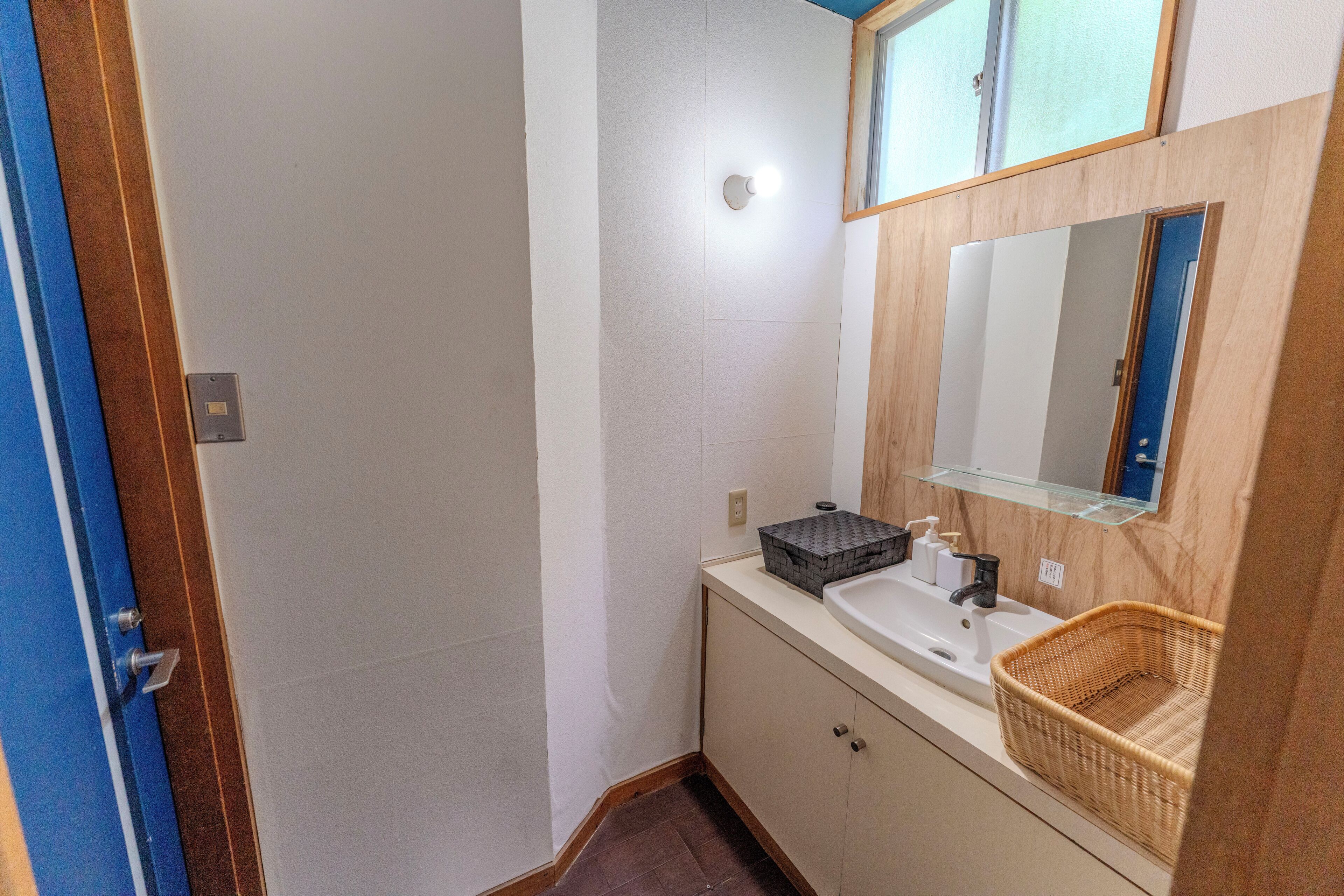 A bathroom with a sink, mirror, and a wicker basket.