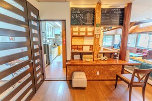 A cozy cafe interior with a wooden counter, seating area, and a chalkboard menu. - RETOPIA AIZU (Bandai)