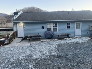 A small, single-story building with a gravel driveway and picnic tables.