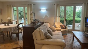 A living room with a sofa, a dining table, and chairs. There is a TV on a stand and a lamp on a table. - Family House in Provence with Pool and Garden (Draguignan)