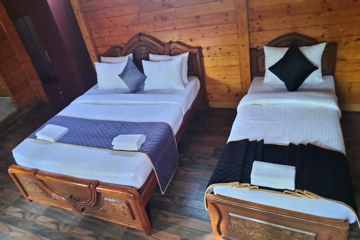 Two wooden beds with white linens and pillows, a wooden door, and a wooden floor.