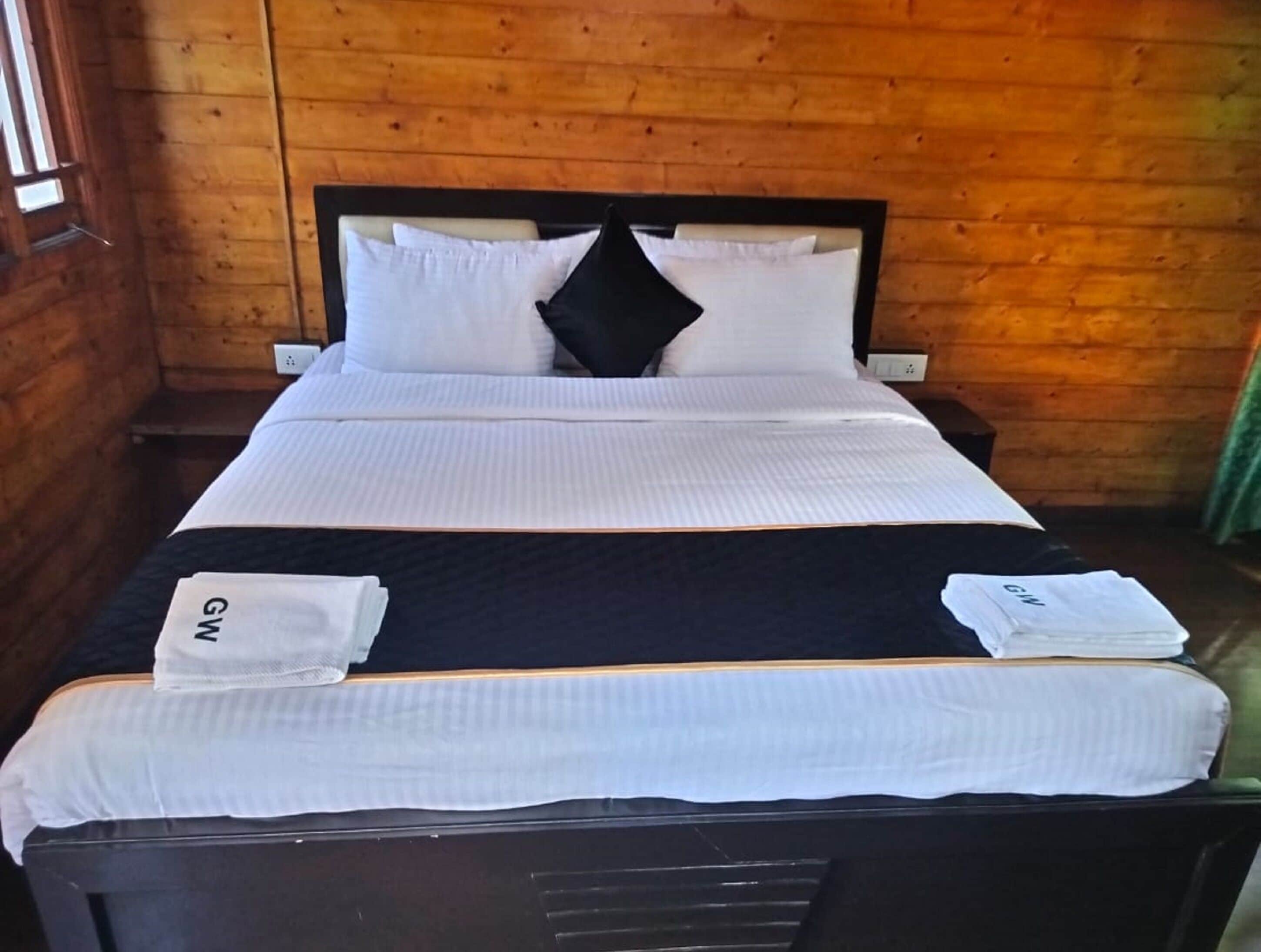 A wooden room with a bed, white bedding, and a black headboard.