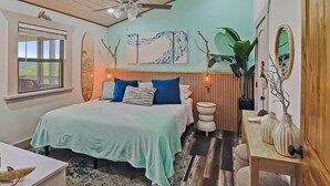 Een slaapkamer met een bed, een plafondventilator, een raam en een kunstwerk aan de muur.