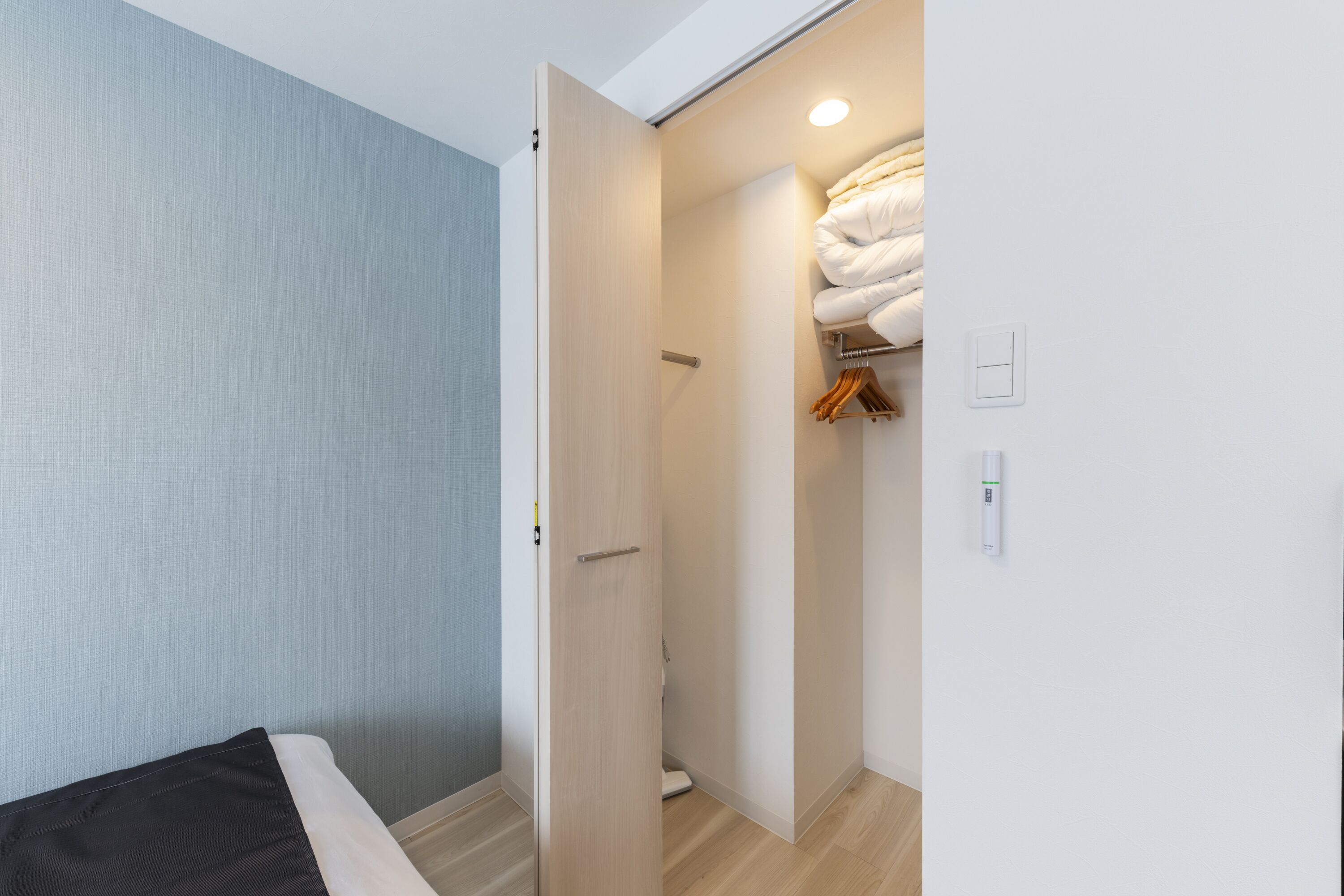 A bedroom with a bed, a closet with hanging clothes, and a bathroom with a toilet and sink.
