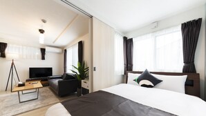 A modern hotel room with a large bed, a flat-screen TV, a sofa, and a desk. - SERENADE Chitose MS103 (Chitose)