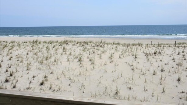 Een strand met een zandige voorgrond en helder uitzicht op de oceaan.