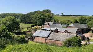 A rural village with stone buildings, a river, and green fields. - The Coach House (Haywards Heath)