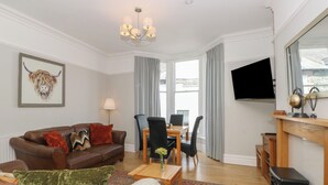 A living room with a sofa, chairs, a coffee table, a fireplace, and a television. - Baystones (Keswick)