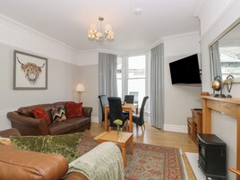 A living room with a sofa, chairs, a coffee table, a fireplace, and a television.