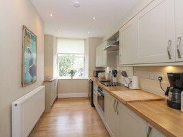 A modern kitchen with white cabinets, a wooden countertop, and a window with a view of greenery.