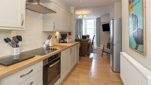 A modern kitchen with a wooden countertop, stainless steel appliances, and a dining area with a view. - Baystones (Keswick)