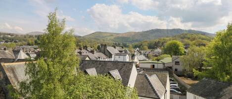 A residential area with houses, trees, and hills in the background.