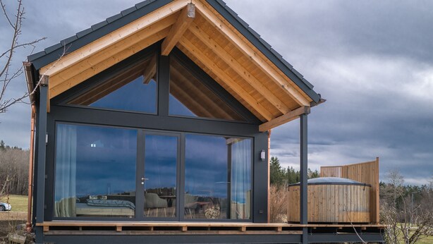 A modern cabin with a large glass window, a wooden deck, and a metal roof. - Neu Gebautes Chalet im Bayerischen Wald (Hohenau)