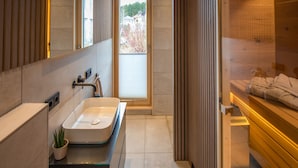 A modern bathroom with a large mirror, a sink, and a wooden sauna area. - Neu Gebautes Chalet im Bayerischen Wald (Hohenau)