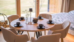 A round dining table with six chairs, a vase with flowers, and tea sets. - Neu Gebautes Chalet im Bayerischen Wald (Hohenau)
