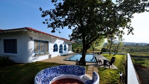Una casa bianca con dettagli blu, una piscina e un patio con mobili da esterno.