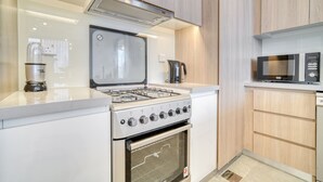 Una cocina moderna con estufa a gas, horno, microondas y cafetera.