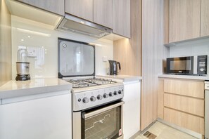 A modern kitchen with a gas stove, oven, microwave, and a coffee maker. - Elegant 2BR w/ Breathtaking Marina Balcony (Dubai)