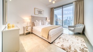 Una habitación de hotel moderna con una cama grande, vistas a la ciudad, un área de descanso y un escritorio.
