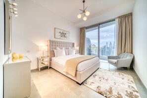 A modern hotel room with a large bed, a city view, a sitting area, and a desk. - Elegant 2BR w/ Breathtaking Marina Balcony (Dubai)