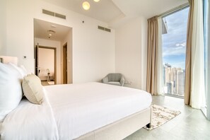 Ein modernes Hotelzimmer mit einem großen Bett, Blick auf die Stadt und einer kleinen Sitzecke.