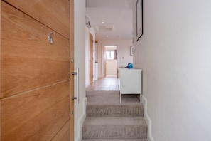 Stairs lead to a room with a door and a console table.