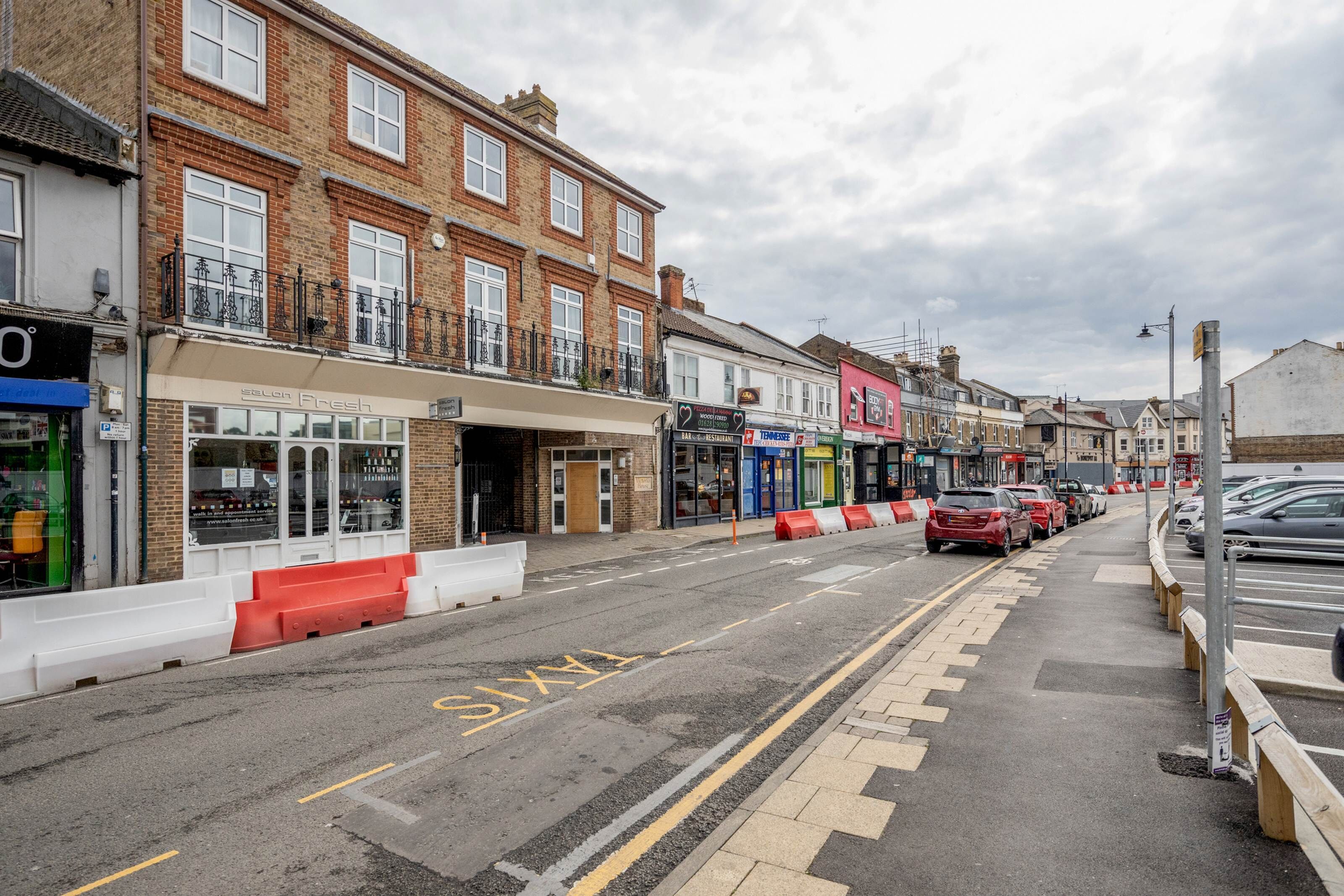 A street with shops, including a pharmacy and a restaurant.