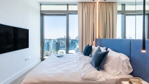 Ein modernes Hotelzimmer mit einem großen Bett, einem flachbildfernseher an der Wand und Blick auf die Stadt durch große Fenster.