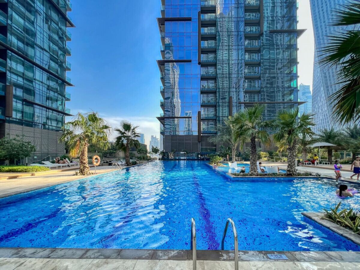A swimming pool surrounded by palm trees and modern buildings.