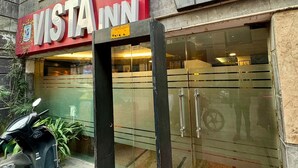 A building with a 'VISTA' sign, a glass door entrance, and a scooter parked outside. - Hotel Vista Inn (New Delhi)