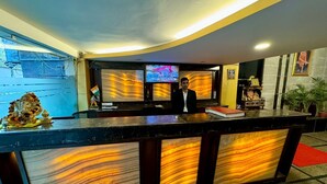 A reception desk with a marble-like design, a television screen, and a statue of a deity. - Hotel Vista Inn (New Delhi)