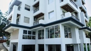 A modern multi-story building with a swimming pool in front. - Goan Fiesta Ultra Luxury Suite Calangute (Calangute)