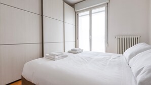 A modern bedroom with a large bed, a radiator, and a window with blinds. - Italianway Comfort - Meda 27 B (Milan)