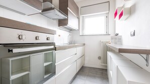 A modern kitchen with white cabinetry, a built-in oven, and a window providing natural light. - Italianway Comfort - Meda 27 B (Milan)