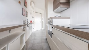 A modern kitchen with white cabinetry, stainless steel appliances, and a wooden countertop. - Italianway Comfort - Meda 27 B (Milan)