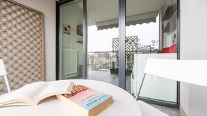 A balcony with a table, a book, and a view of buildings. - Italianway Comfort - Meda 27 B (Milan)