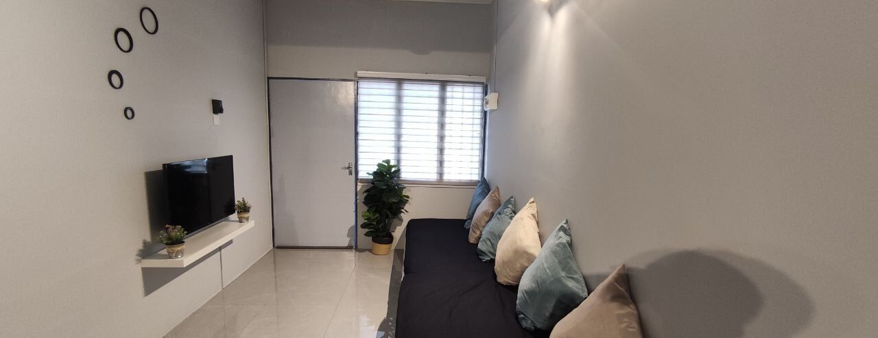 A modern bedroom with a bed, a TV on a shelf, a potted plant, and a door leading to another room.