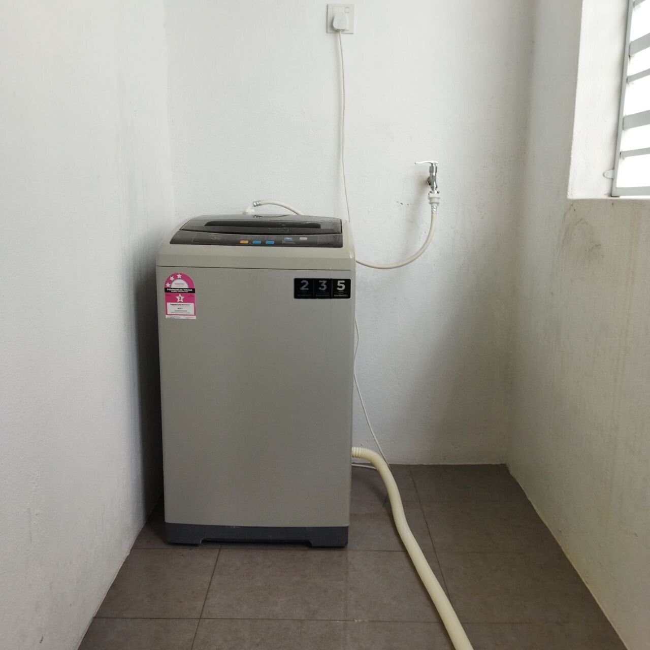 A compact, grey portable heater with a digital display and a control panel, connected to a power outlet on a tiled floor.