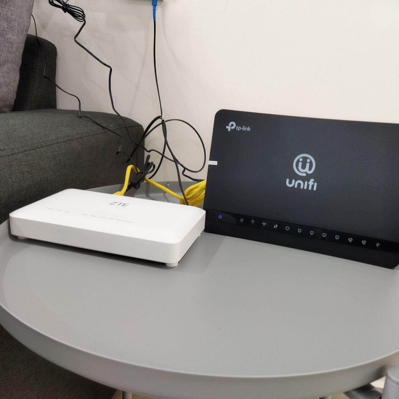 A white ZTE router and a black UniFi access point on a round table.