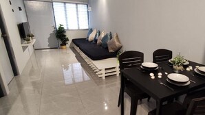 Un comedor moderno con una mesa negra preparada para cuatro personas, un sofá con cojines y una planta en maceta.